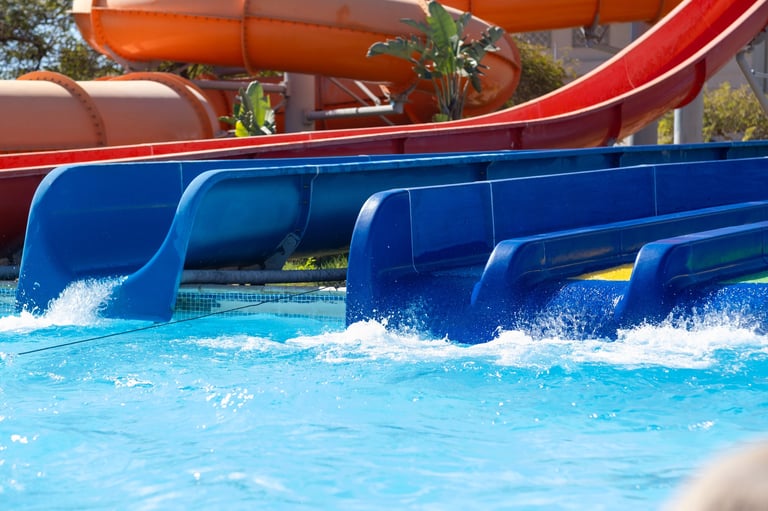 Toboganes de agua coloridos en parque acuático tropical con diversión familiar