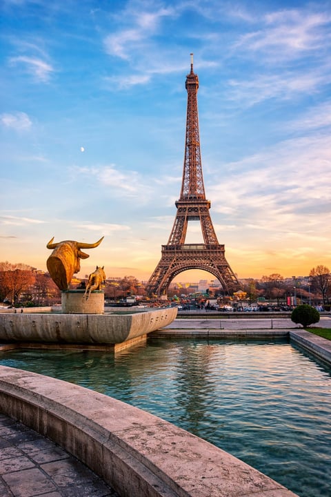 Eiffel Tower in Paris with golden bull sculpture beside turquoise river at sunset
